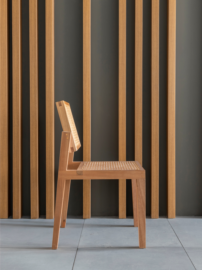 Side view of a wood chair against similar wood paneling.